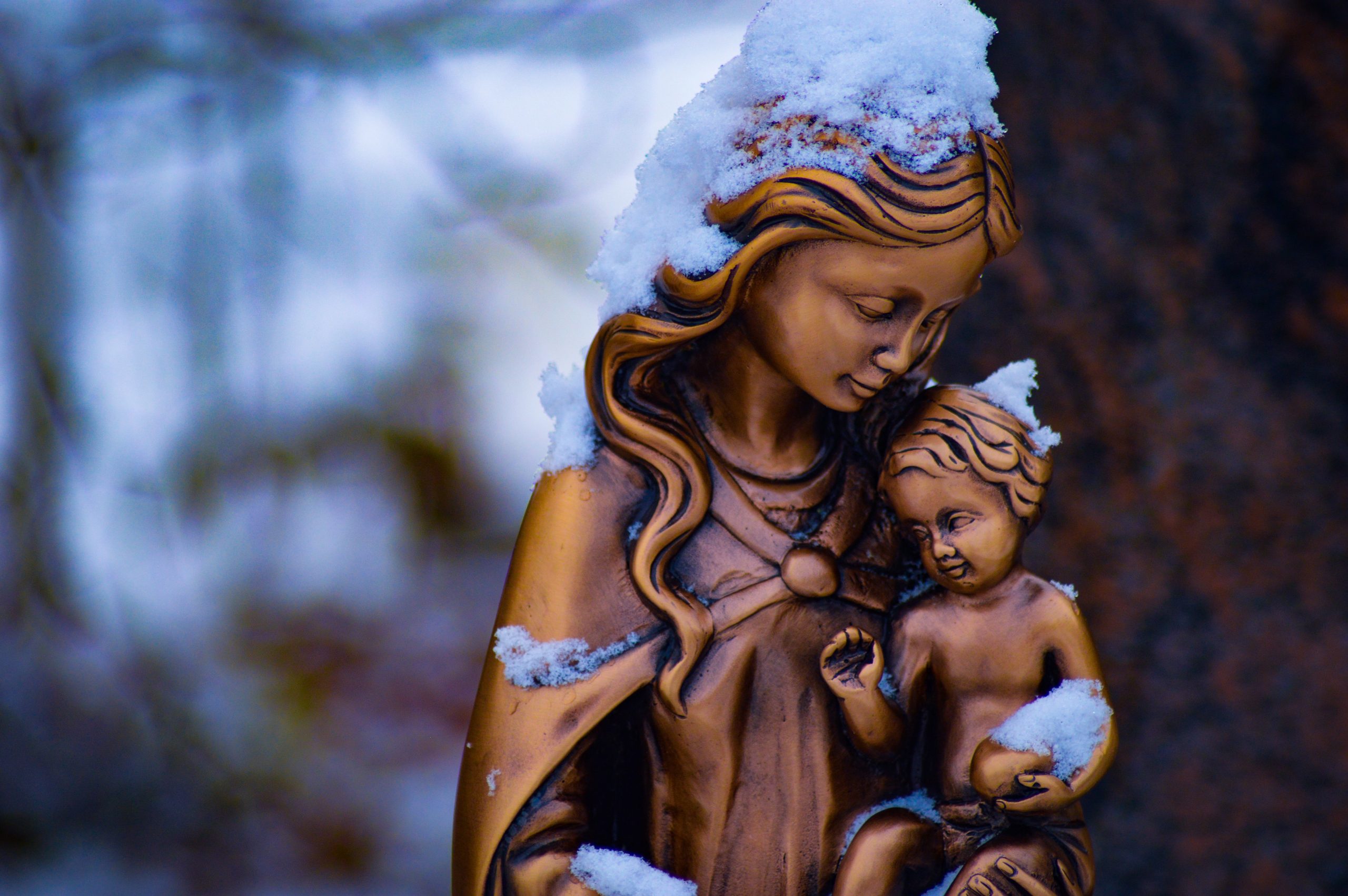 brown mother and child statue partially covered with snow